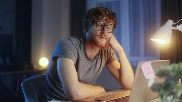 Portrait of exhausted young red haired man student juggles crumpled papers with failed ideas while take a break at home at late night Tired male with creative block or lack of inspiration indoors	