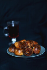 Plate of homemade cinnamon rolls and cup of tea. Dark background, selective focus.