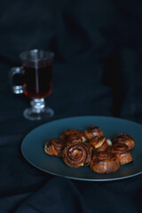 Plate of homemade cinnamon rolls and cup of tea. Dark background, selective focus.