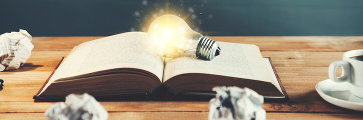 light bulb on vintage book with crumpled papers