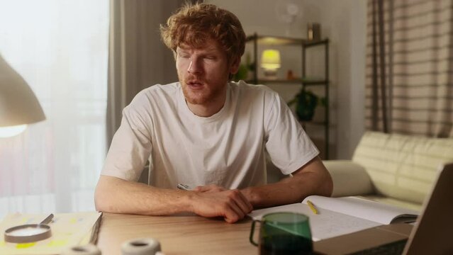 Unhappy young red haired man feeling annoyed when getting message on smartphone at home workplace Nervous male having problem on study or work conflict online indoors