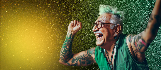 70 year old senior citizen with green hair, tattoos and earrings stretches his arms up exuberantly. He is happy and laughing. There is green glitter dust in the background.