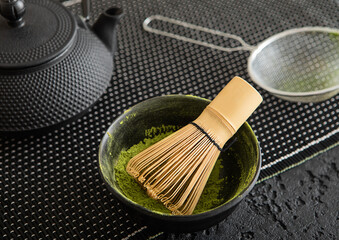 Japanese iron kettle with matcha green tea powder with whisk and spoon and bowl with sifter on...