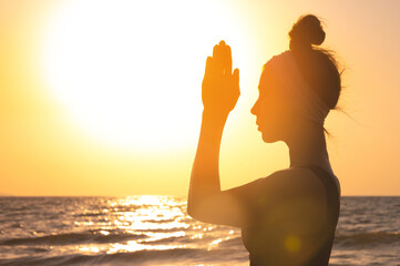 Happy woman silhouette, raises her hands to the sun at dawn. Freedom and spirituality concept