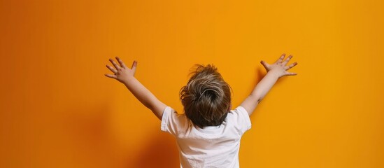 Portrait of happy little boy raised hands on yellow background - obrazy, fototapety, plakaty