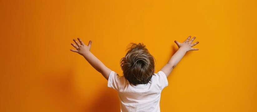 Portrait of happy little boy raised hands on yellow background