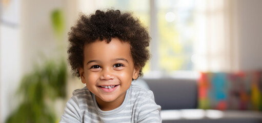 Portrait of a happy cute African American kid with afro fluffy hair looking at the camera. Black beautiful happy healthy child. A child sits in a children's room with toys, in a private kindergarten.