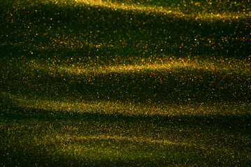 Stunning overflows of golden particles in green fluid. Golden dust glitters flows in green liquid...