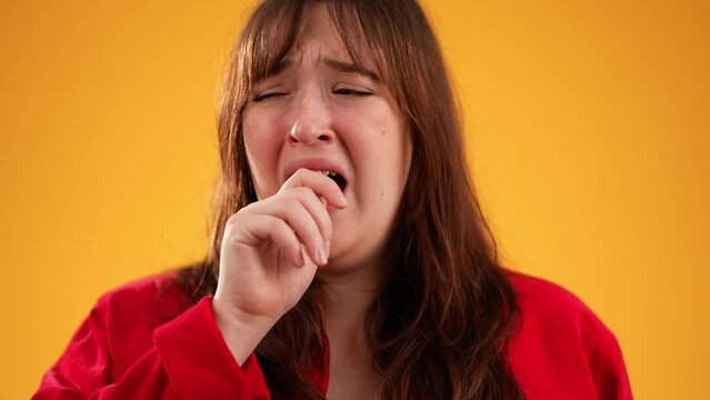 Pretty brunette young woman 20s did not get enough sleep last night after party and barely got up in the morning yawning. Portrait isolated on yellow background in studio in slow motion