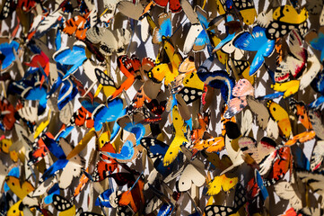 A wall of colorful butterflies made out of metal in the sun