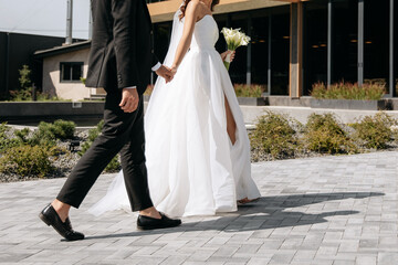 The bride with a bouquet leads the groom. Black wedding suit and dress. Luxury wedding