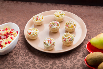 on the table is a salad in tartlets in a plate on a brown tablecloth