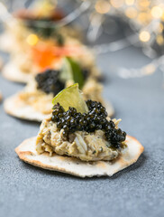 Holiday canapes with red and black caviar, on crackers festive silver Christmas decoration, copy space, selected focus, narrow depth of field