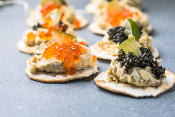 Holiday canapes with red and black caviar, on crackers festive silver Christmas decoration, copy space, selected focus, narrow depth of field