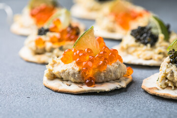 Holiday canapes with red and black caviar, on crackers festive silver Christmas decoration, copy space, selected focus, narrow depth of field