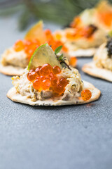 Holiday canapes with red and black caviar, on crackers festive silver Christmas decoration, copy space, selected focus, narrow depth of field