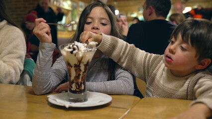 Siblings Sharing Ice Cream with Whipped Cream at Restaurant Diner - Children Enjoying Sugar Dessert...