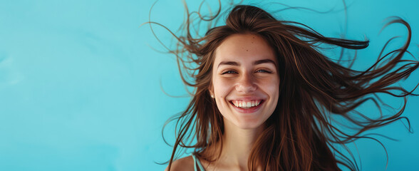 Smiling young pretty woman with brunette brown long groomed hair isolated on flat blue background with copy space. Perfect hair care products banner template, hair salon.