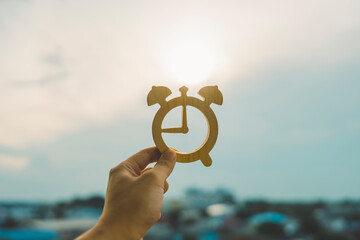 Hand holding the time symbol with cityscape on panoramic skyline and buildings in the morning...