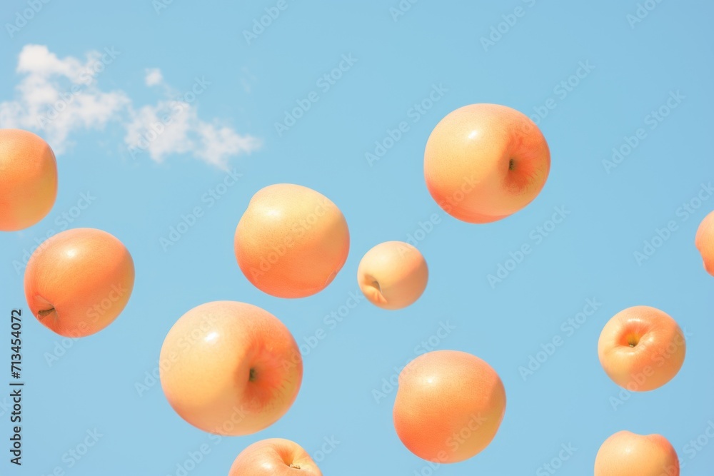 Poster a group of oranges floating in the air with a cloud in the sky behind them on a sunny day.