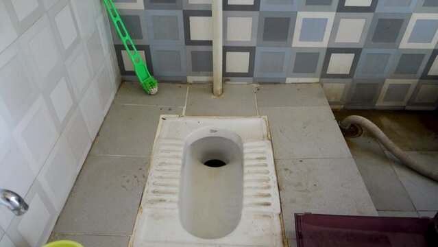 An Asian squat style toilet and bathroom in an unhygienic condition. India