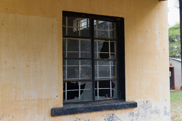 Fototapeta na wymiar broken window with burglar bars on an old building, colonial architecture vintage in a village in Botswana, design elements and textures