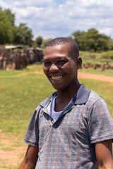young african man in the village standing on the lawn with a big smile