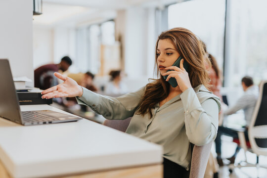 Confident female entrepreneur analyzing, planning, and discussing solutions over a business call in the office. Focused on individual tasks, she contributes to the company's growth.