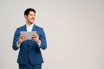 The handsome Hispanic man in blue formal suit smiling while using the tablet provides a relatable...