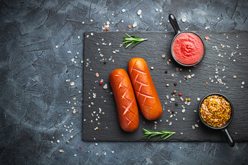 Grilled sausages with spices on a stone plate. Dark background