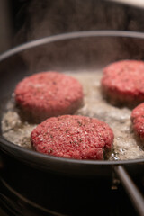 Burger paddies of high quality groundbeef searing on hot pan. authentic look.