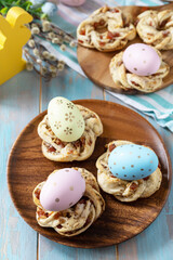 Sweet italian Easter bread rings from puff pastry and dyed eggs on a wooden blue tabletop.