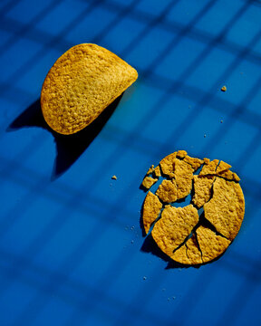 Golden and crusty potato chips on blue background. Minimalistic food photo. 