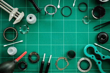 bunch of disassembled camera lens and lens repairing tools equipment laying on green service table waiting for fix and cleaning