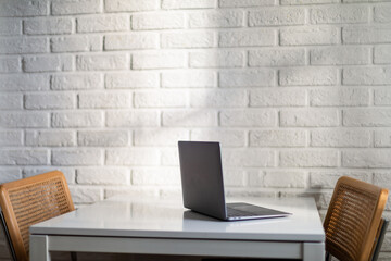 Laptop computer against white brick wall