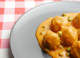 Close up, homemade plate of meatballs with tomato sauce and peas.