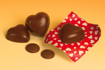 Italian food product, heart shaped milk cocoa chocolates on orange background.