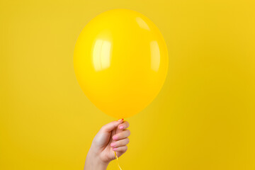 Hand holding an inflated yellow balloon