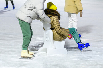 Ice skating on an outdoor skating rink. People, tourists skate, learn to skate with helper on ice rink. Winter fun.