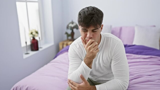 Anxious young hispanic man, stressed and biting nails in bedroom, embodies fear and nervousness