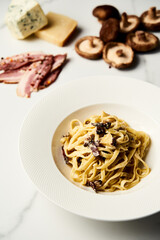 Alfredo Pasta with shiitake mushrooms and artichokes on white marble background. Minimalistic food photo. 