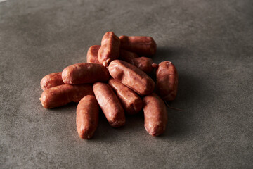 Mini pork sausages on grey concrete background, loft style. Raw and uncooked. 