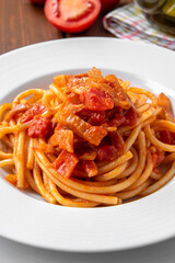 Piatto di bucatini all'amatriciana, tradizionale ricetta di pasta della cucina laziale condita con guanciale, pomodori e pecorino, cibo italiano  