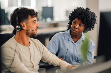 Portrait of an interracial call center manager discussing with colleague.