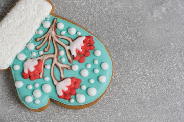 Christmas cookies in shape mitten, decorated with icing depicting rowan tree, sprinkled with snow. Magic holiday every sweet detail.