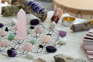 A close up image of a crystal healing grid with sage smudge sticks and crystal towers. 