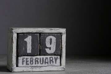 February 19 on wooden calendar, on dark gray background.