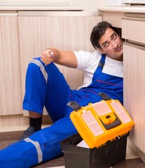 Young repairman working at the kitchen