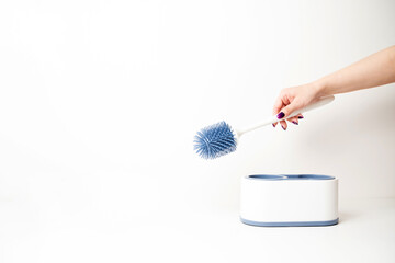 Closeup of female hand holding toilet brush on a white background with space for text. Cleaning...