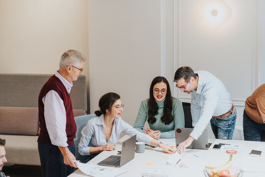 Mixed race team of business people working together on a project in modern office. They are brainstorming new ideas and solutions for their problems, working in a pleasant atmosphere, indoors.